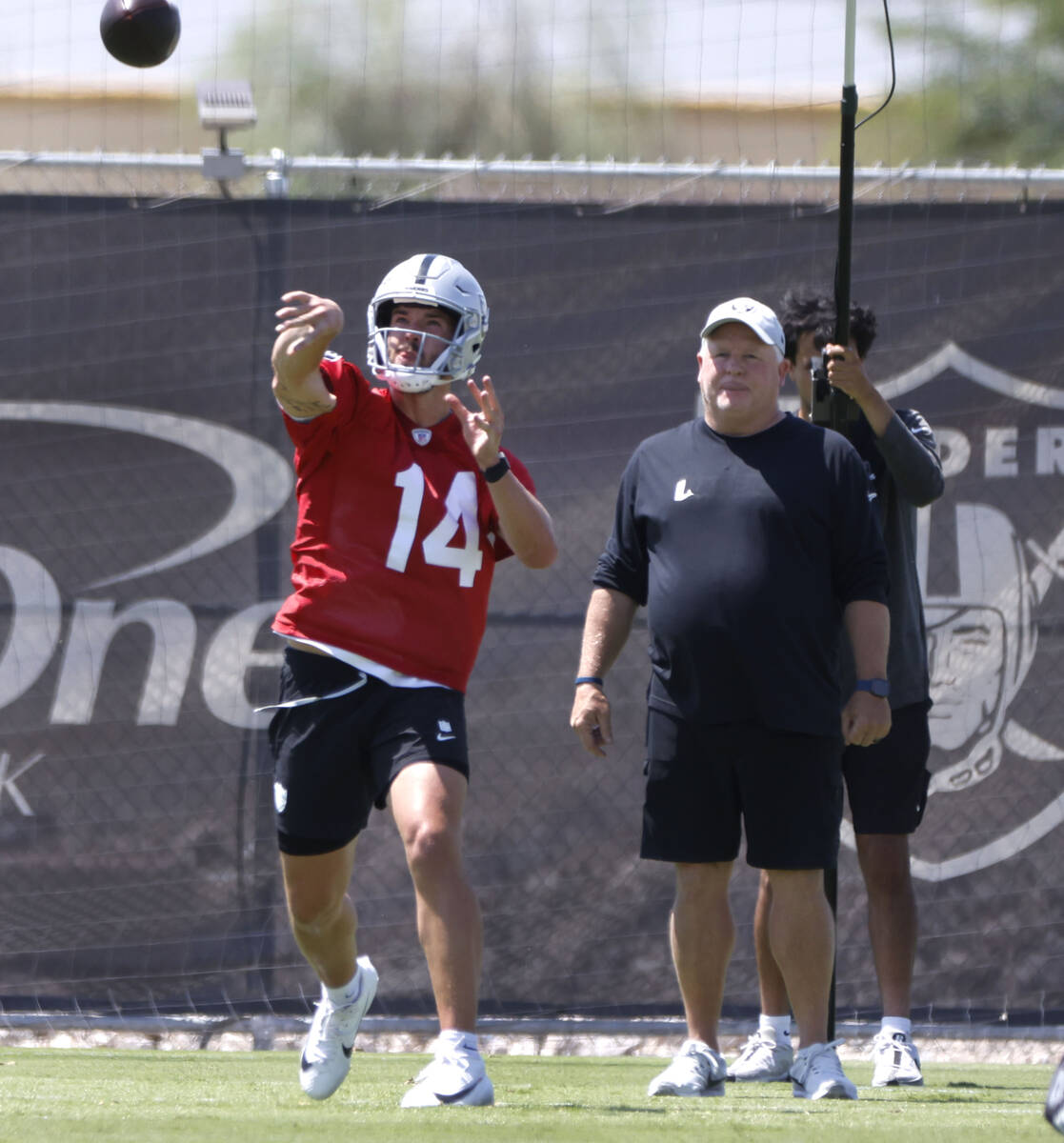 Raiders quarterback quarterback Carter Bradley (14) throws the ball as offensive coordinator Ch ...
