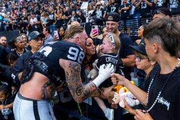 Raiders defensive end Maxx Crosby (98) attempts to get his daughter to stop crying as he greets ...