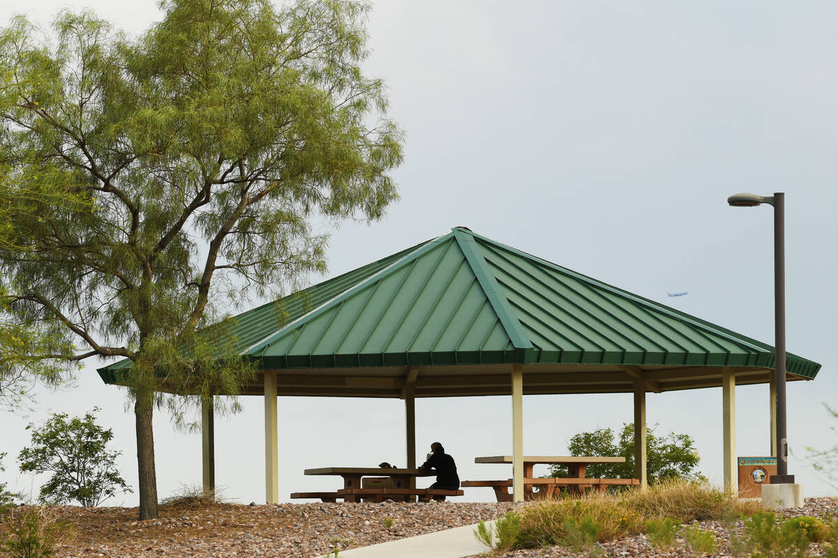 A person sits under a picnic shelter at Lone Mountain Regional Park Wednesday, June 4, 2025, in ...