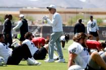 Raiders head coach Pete Carroll encourages his players as they stretch during organized team ac ...