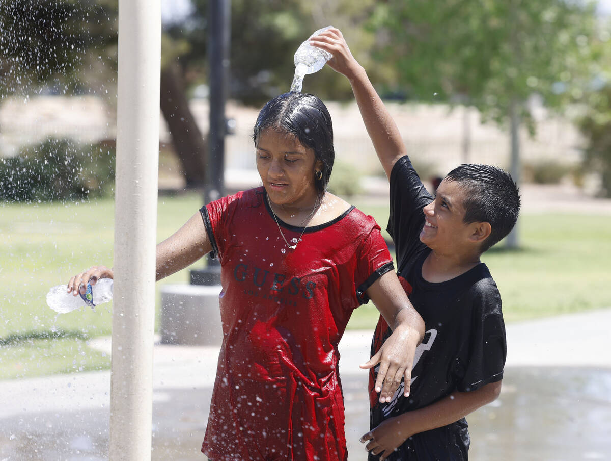 Jose Martinez, 10, pours water on his sister Denise, 12, as they play at Lorenzi Park's splash ...