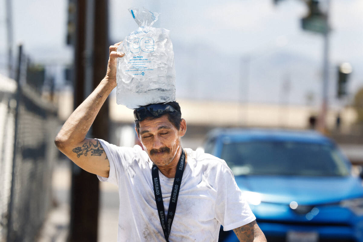 Terry Morris of Las Vegas places a bag of ice on his head as he walks on Washington Avenue duri ...