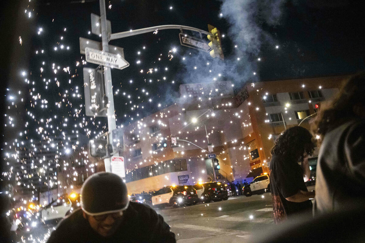 People take cover as a firework explodes during a protest near the Metropolitan Detention Cente ...
