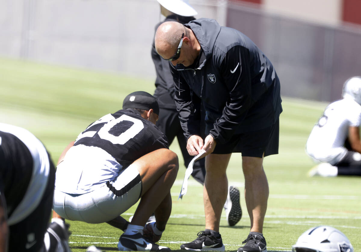 Raiders special teams coordinator Tom McMahon chats with safety Isaiah Pola-Mao (20) during an ...