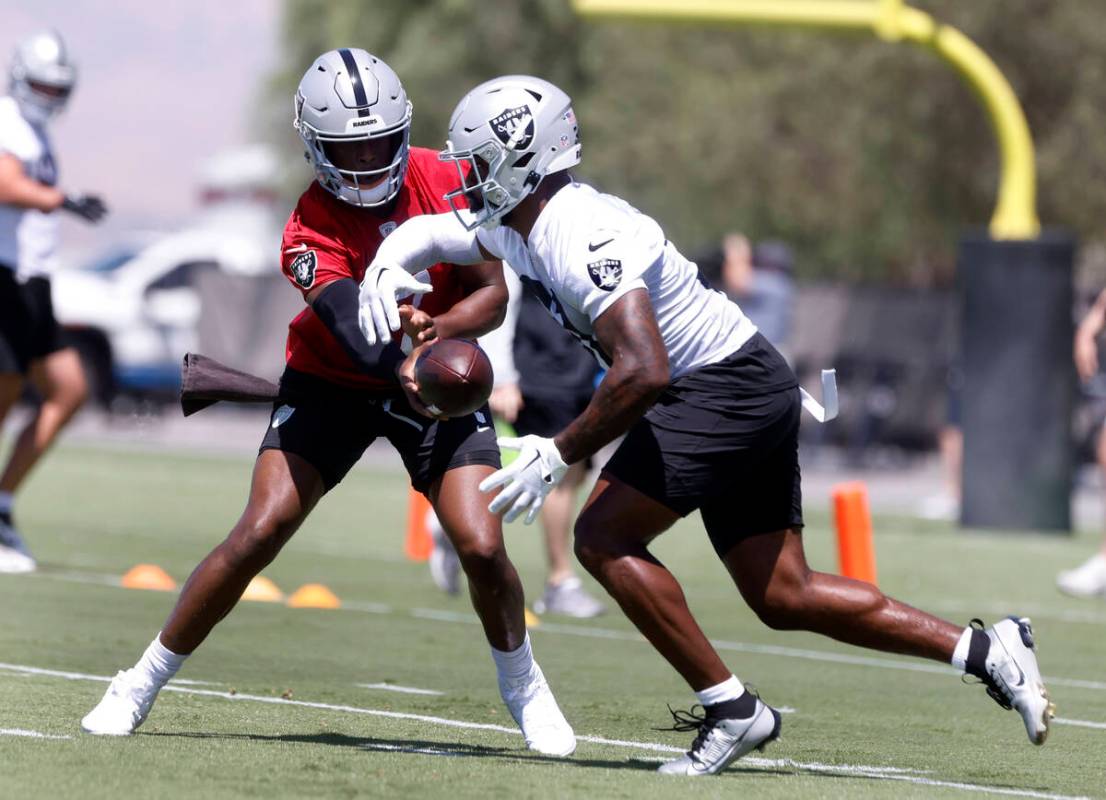Raiders quarterback Geno Smith (7) hands the ball to running back Raheem Mostert (31) during an ...