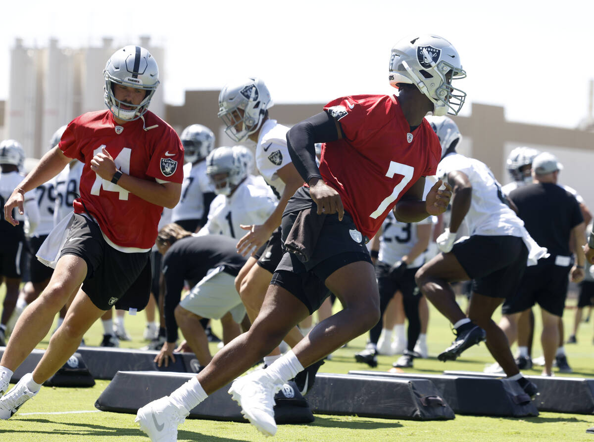 Raiders quarterbacks Geno Smith (7) and Carter Bradley (14) run through a drill during an NFL m ...