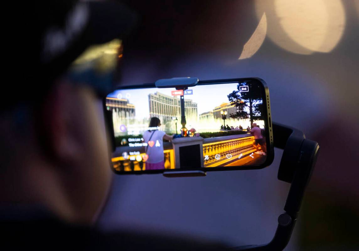 A man livestreams as people gather by the Bellagio Fountains for a vigil in memory of Rodney Fi ...