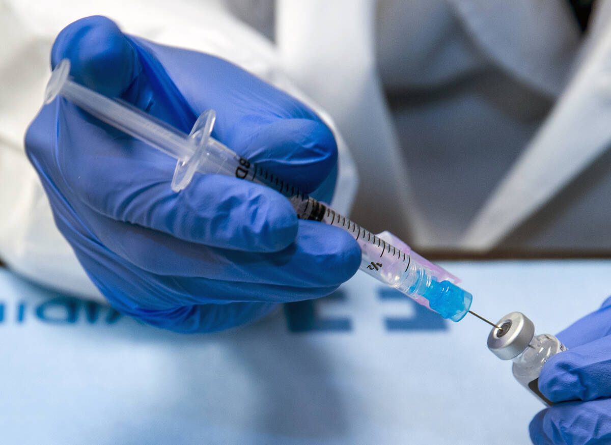 Student pharmacist Wilbur Quimba loads up new syringes with vaccine Wednesday, Dec. 16, 2020, i ...