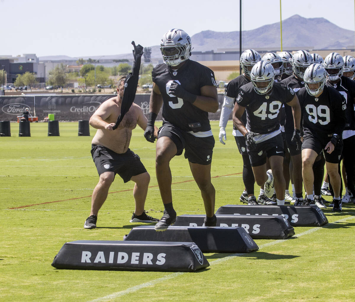 Assistant coach Rip Rowan, left, rallies the defensive players during a drill led by Raiders de ...