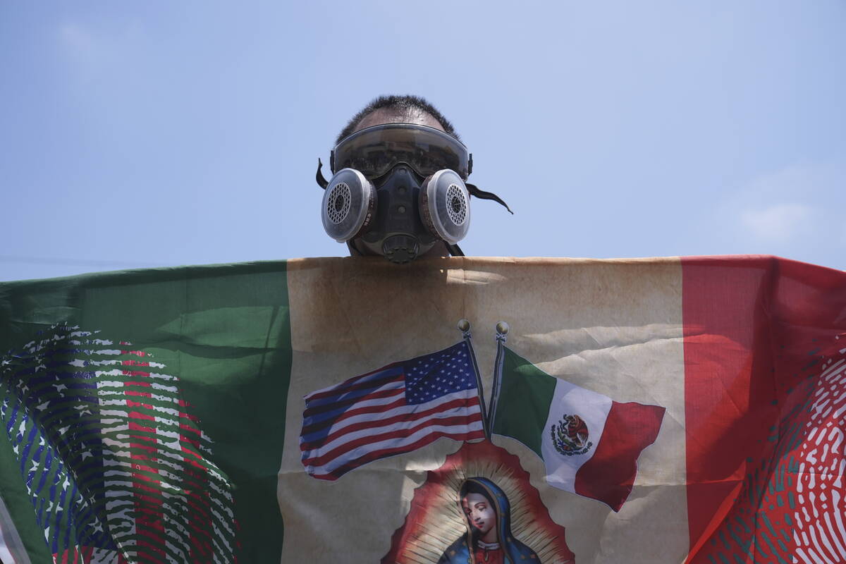 A protester wears a respirator outide a detention center in downtown Los Angeles, Sunday, June ...