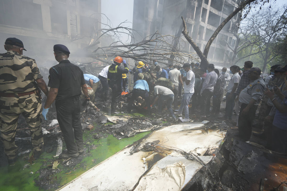 Rescuers work at the site of an airplane that crashed in India's northwestern city of Ahmedabad ...