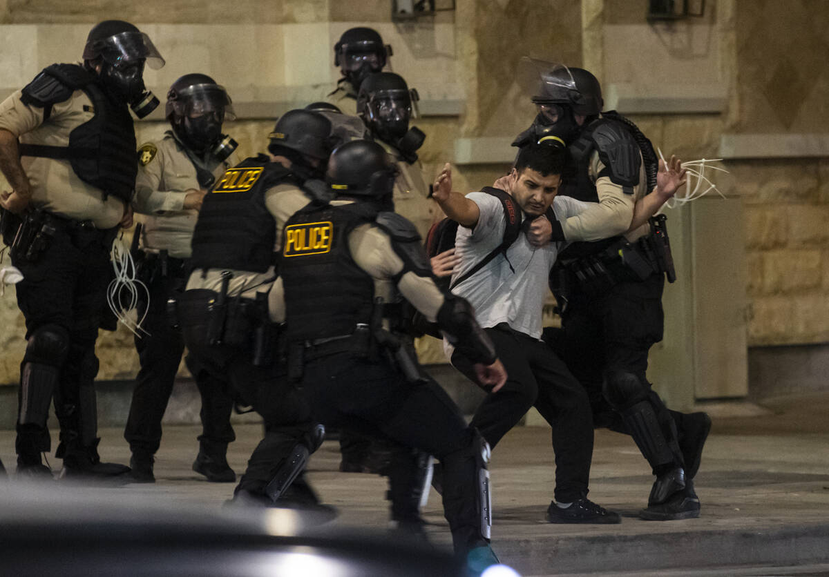 Las Vegas police detain a nonviolent protester before dragging him away on the ground on Wednes ...