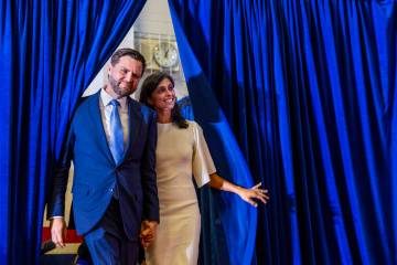 Ohio Senator JD Vance and his wife Usha look out from the side curtains as they arrive on stage ...