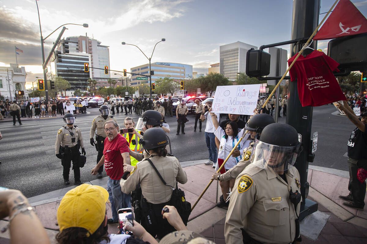 A supporter of President Donald Trump, who was carrying a large flagpole, is detained by police ...
