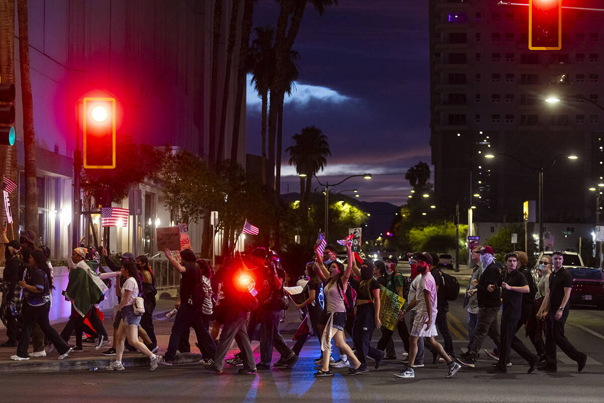People walk along Las Vegas Boulevard while participating in the “No Kings” prote ...