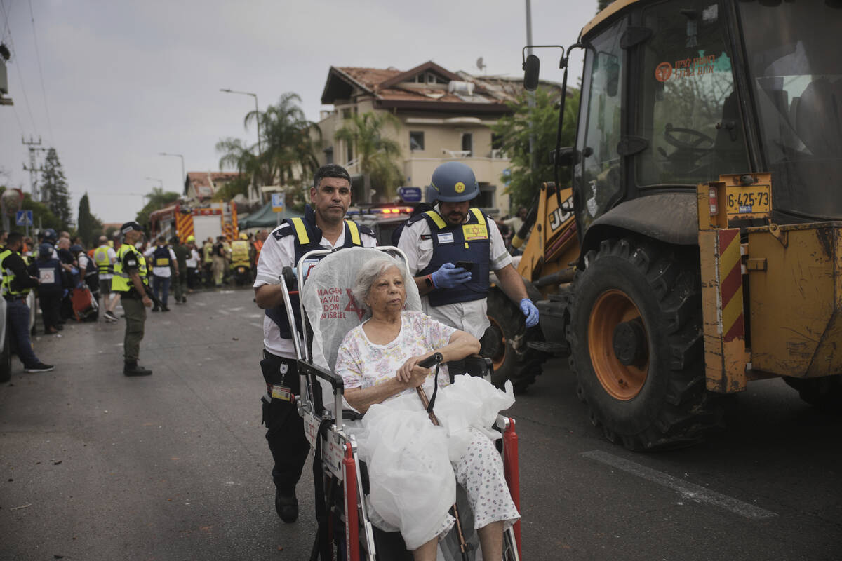 Paramedics evacuate a woman from a site that was struck by a missile fired from Iran, in Rishon ...