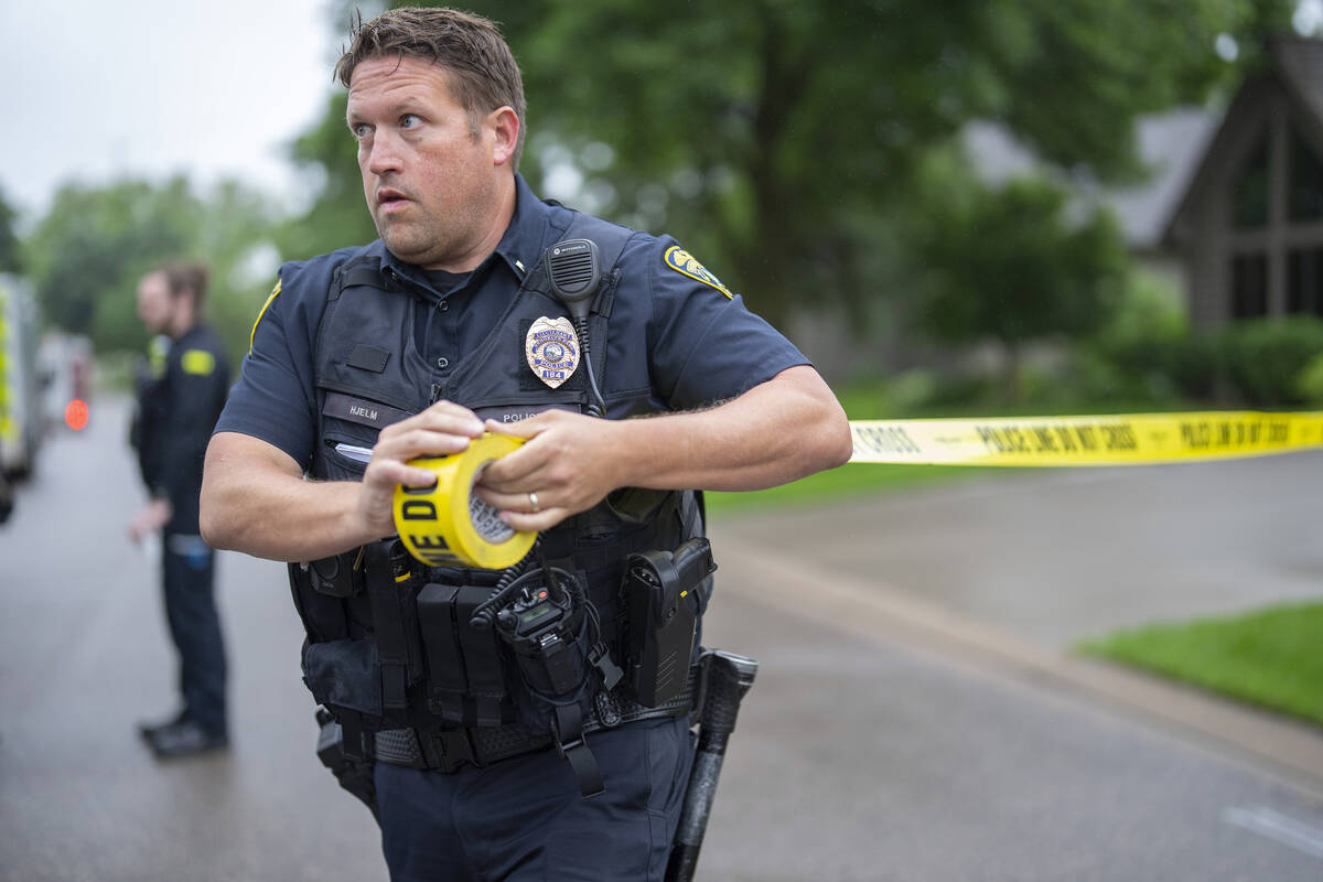 Brooklyn Park Police Lieutenant Hjelm sets up a perimeter with police tape near the scene of a ...