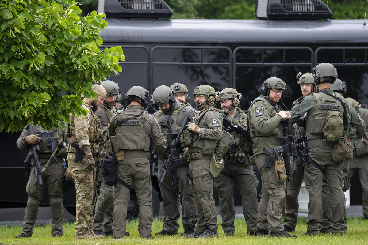 Law enforcement officers including local police, sheriffs and the FBI, stage less than a mile f ...