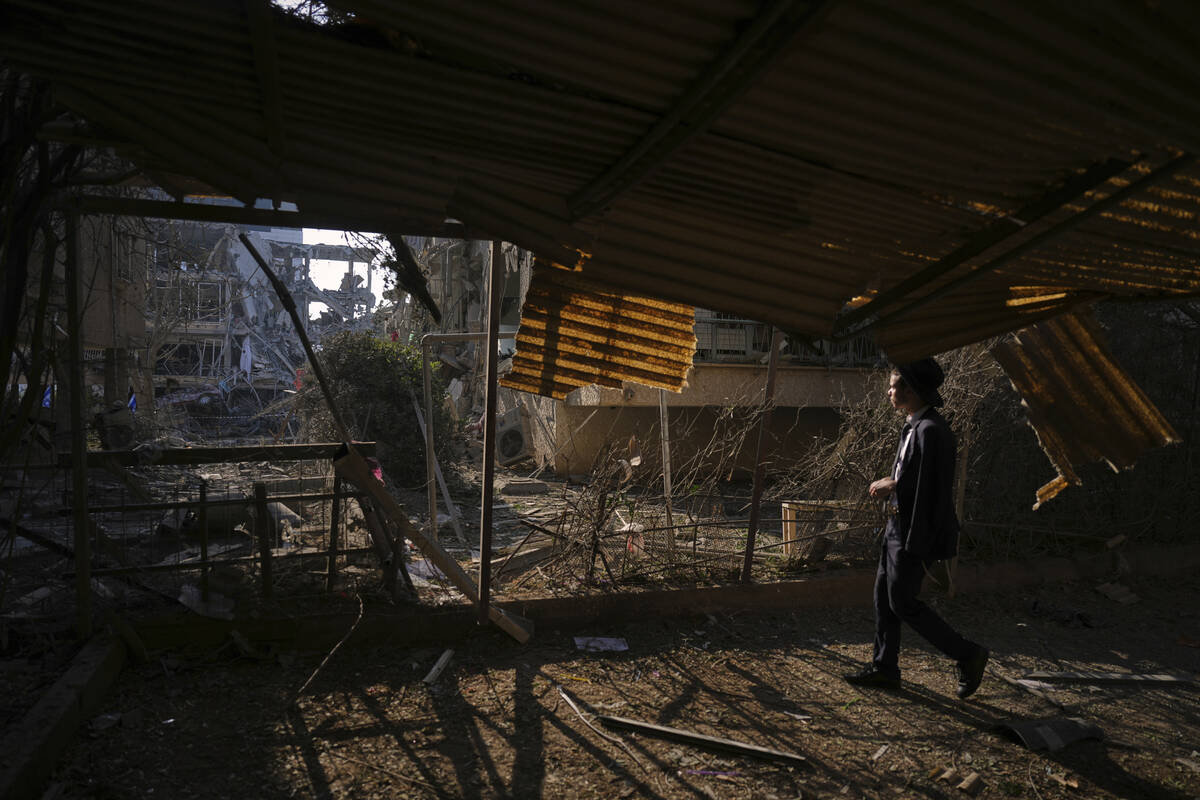 A person looks out at a destroyed residential building that was hit by a missile fired from Ira ...