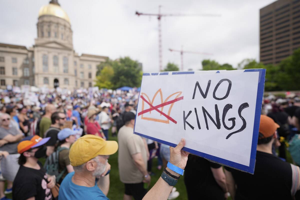 A demonstrator holds a sign during a "No Kings" protest, Saturday, June 14, 2025, in ...