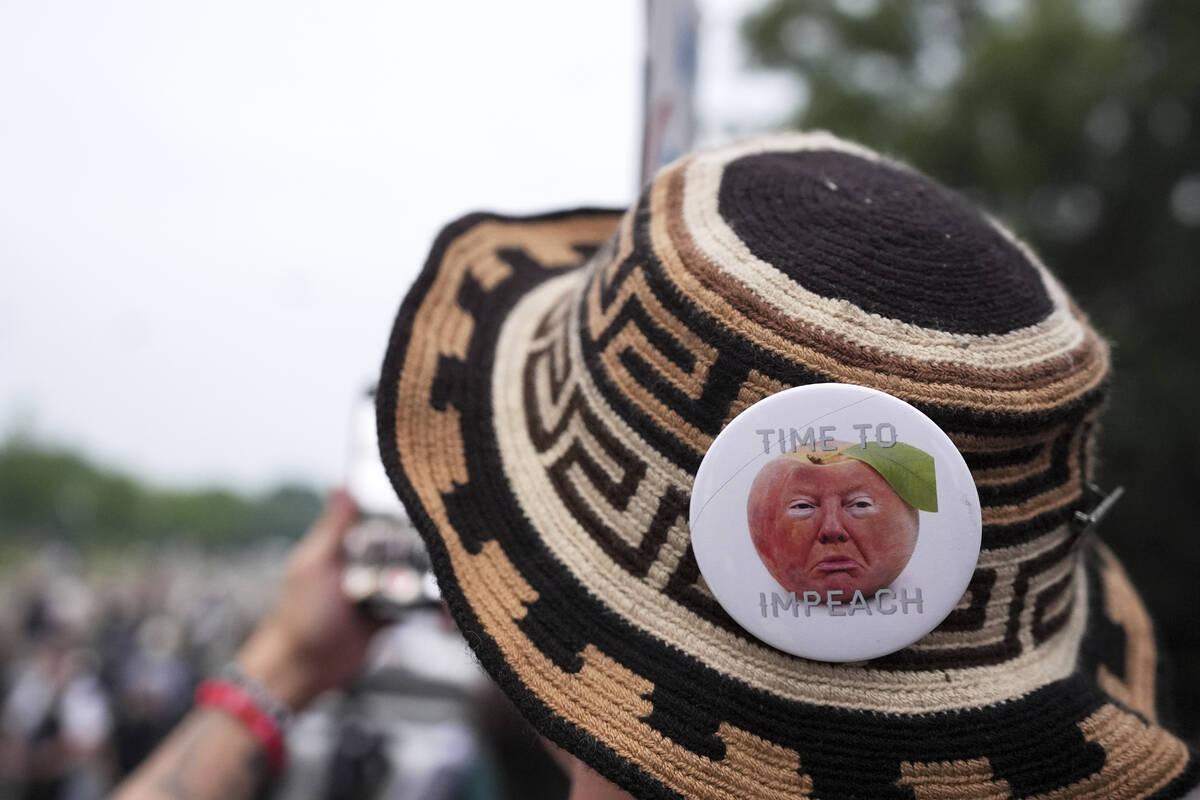 A demonstrator wears a pin stating "time to impeach" during a protest taking place on ...