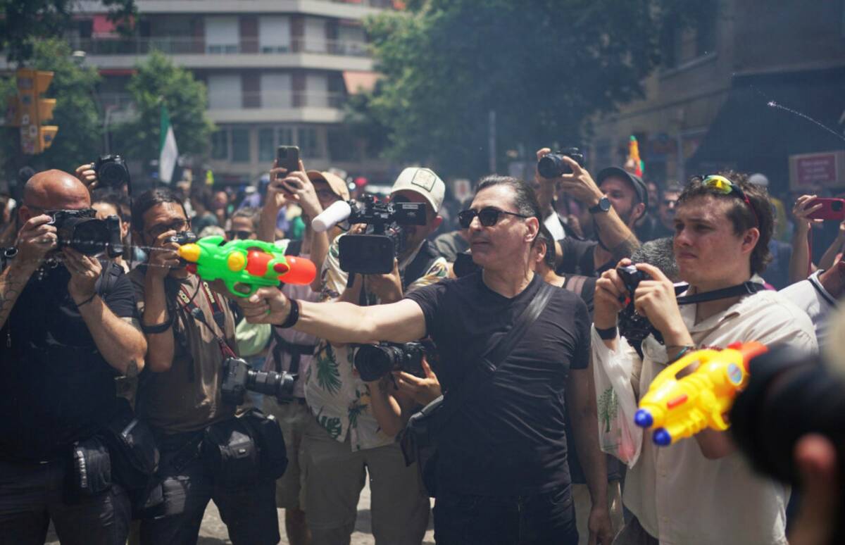 People shoot in the direction of tourists with water guns during a protest against overtourism ...
