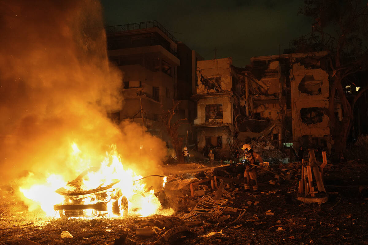 Firefighters work to extinguish a blaze after a missile launched from Iran struck Tel Aviv, Isr ...