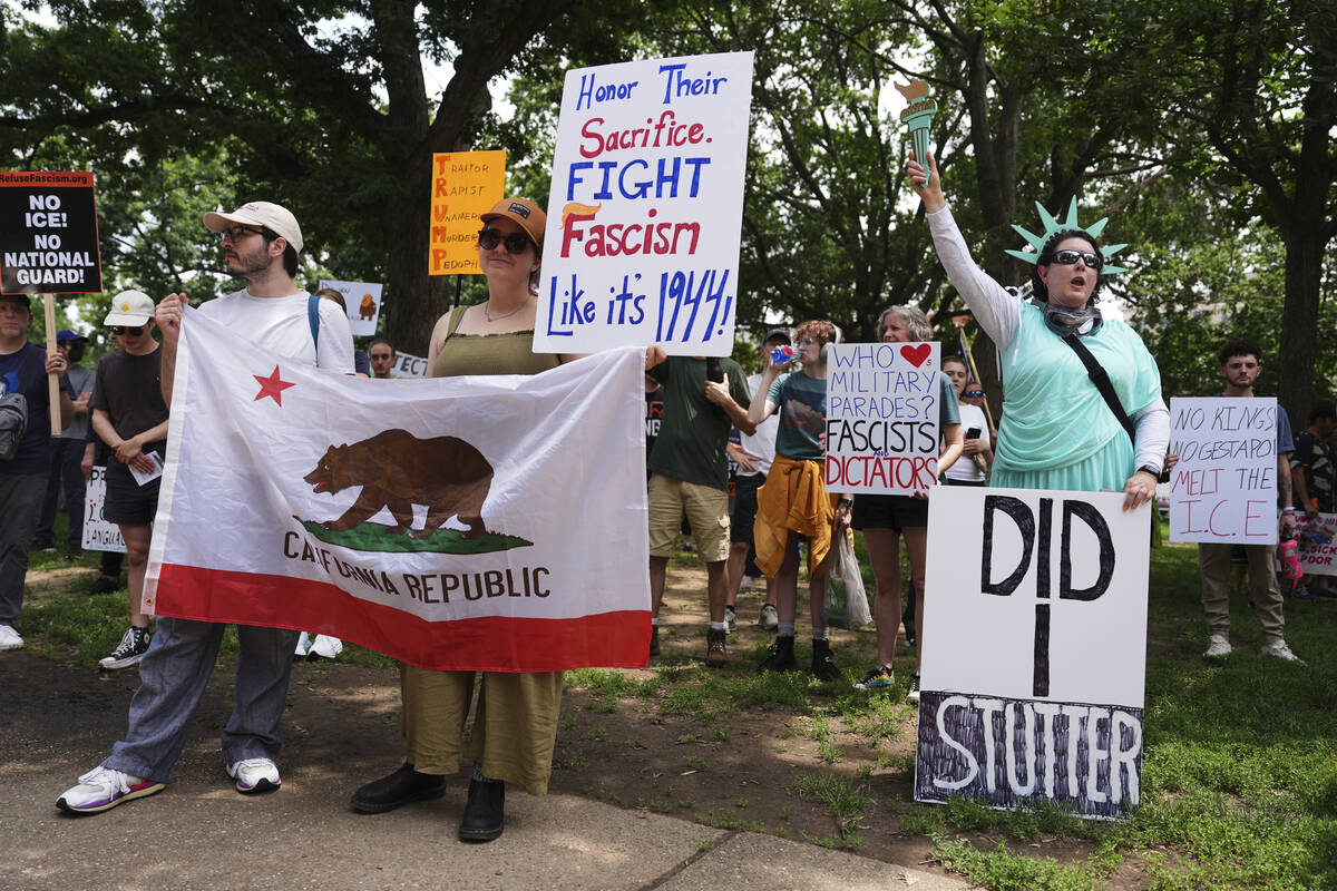 Demonstrators carry signs as they participate in a protest taking place on the day of a militar ...