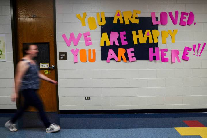 A staff member walks past a message to students that hangs on the wall at Place Bridge Academy, ...