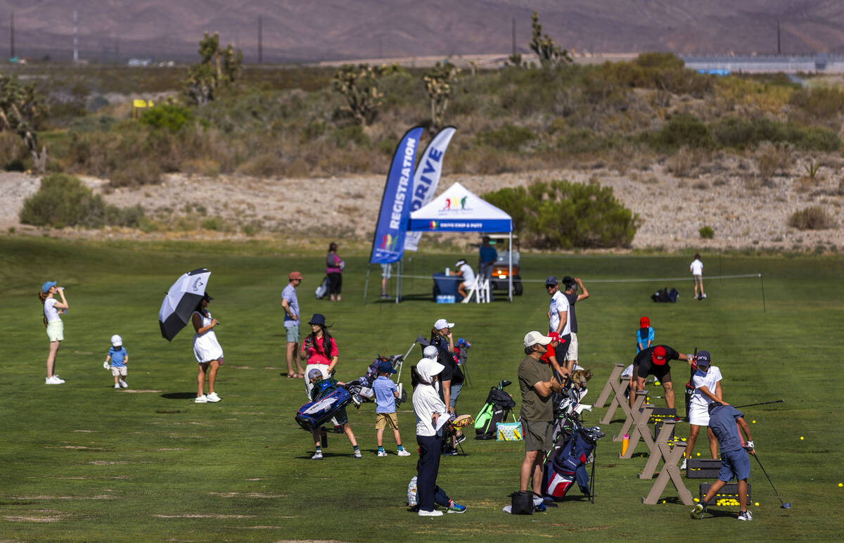 Golfers take some practice drives on the range as others look on awaiting their turns to compet ...