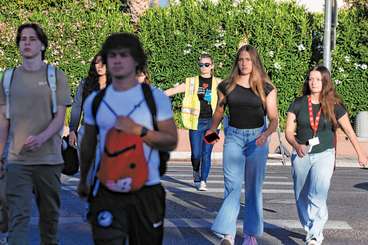 Ashley Brewer, center, a volunteer, helps students cross Buffalo Drive where McKenzie Scott, a ...