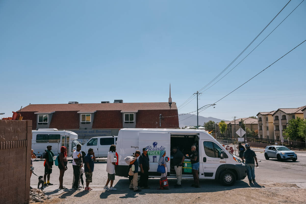 Homeless people line up outside of the Beauty 2 The Streetz van as Shirley Raines hands them dr ...