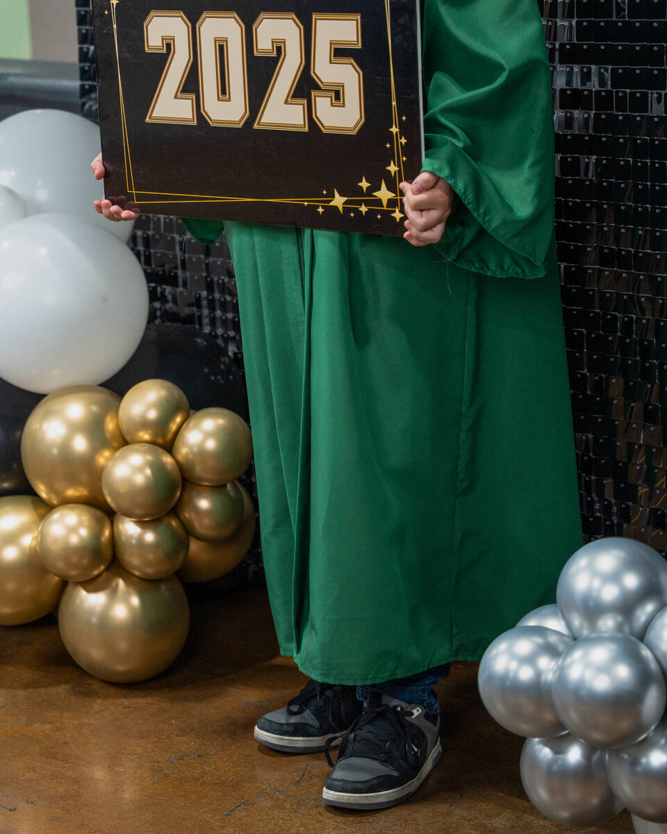 A graduate holds a sign while celebrating their completion of high school during an open house ...