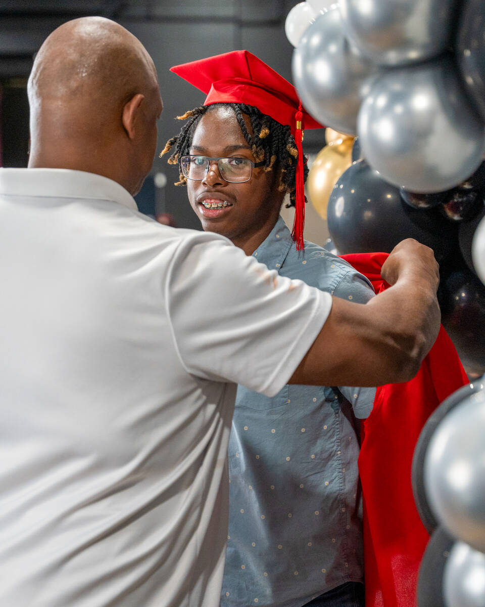 James Renfro helps his foster son, Isaiah Holliday, 18, out of his cap and gown after a photo d ...