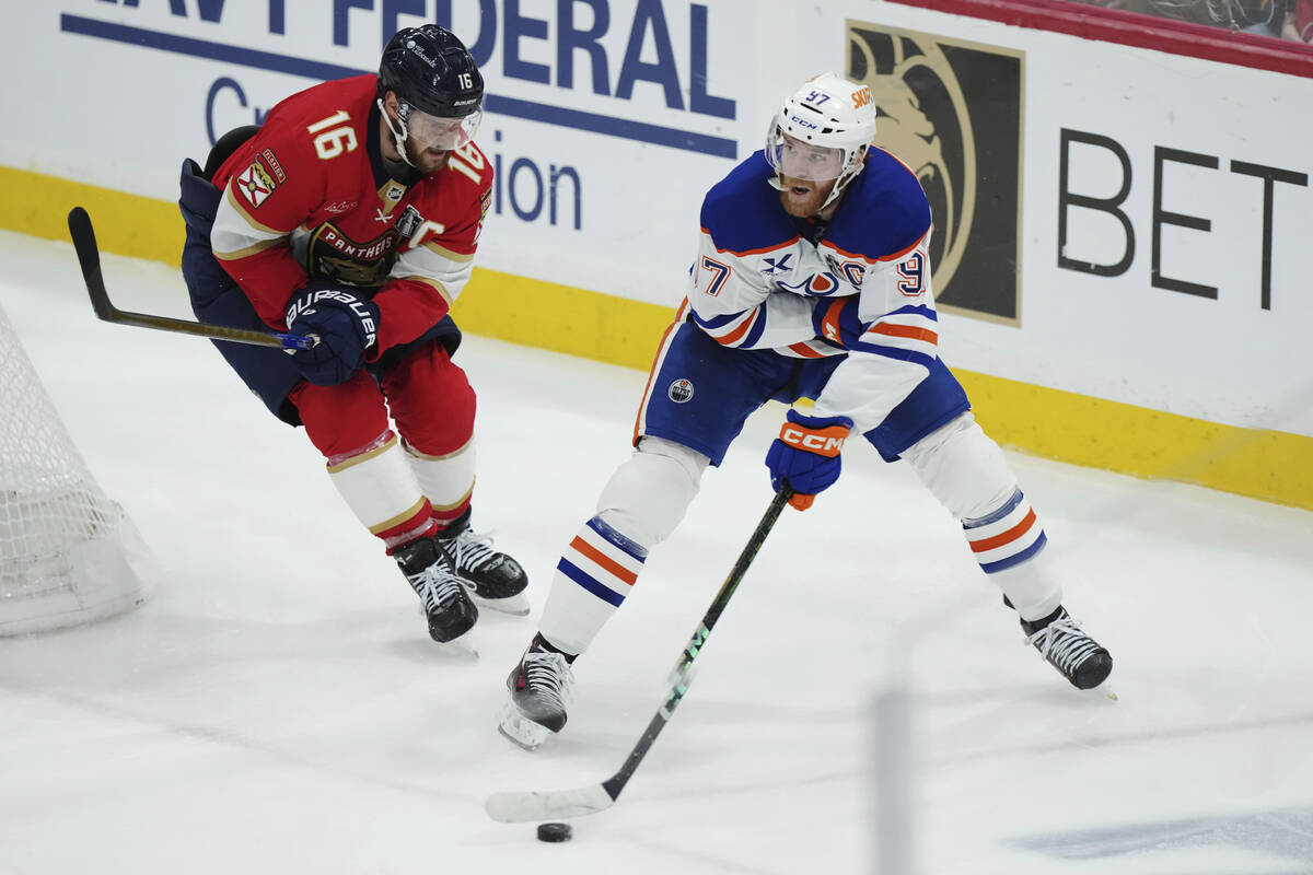 Edmonton Oilers' Connor McDavid (97) protects the puck from Florida Panthers' Aleksander Barkov ...
