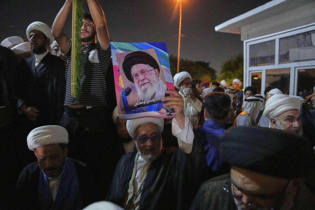 An Iraqi Shiite cleric holds a portrait of Iran's Supreme Leader Ayatollah Ali Khamenei during ...