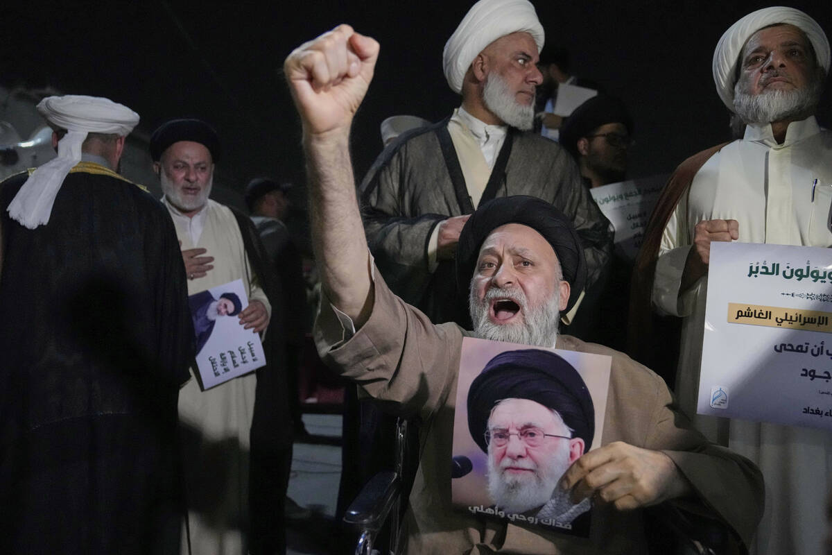 An Iraqi Shiite cleric holds a portrait of Iran's Supreme Leader Ayatollah Ali Khamenei during ...
