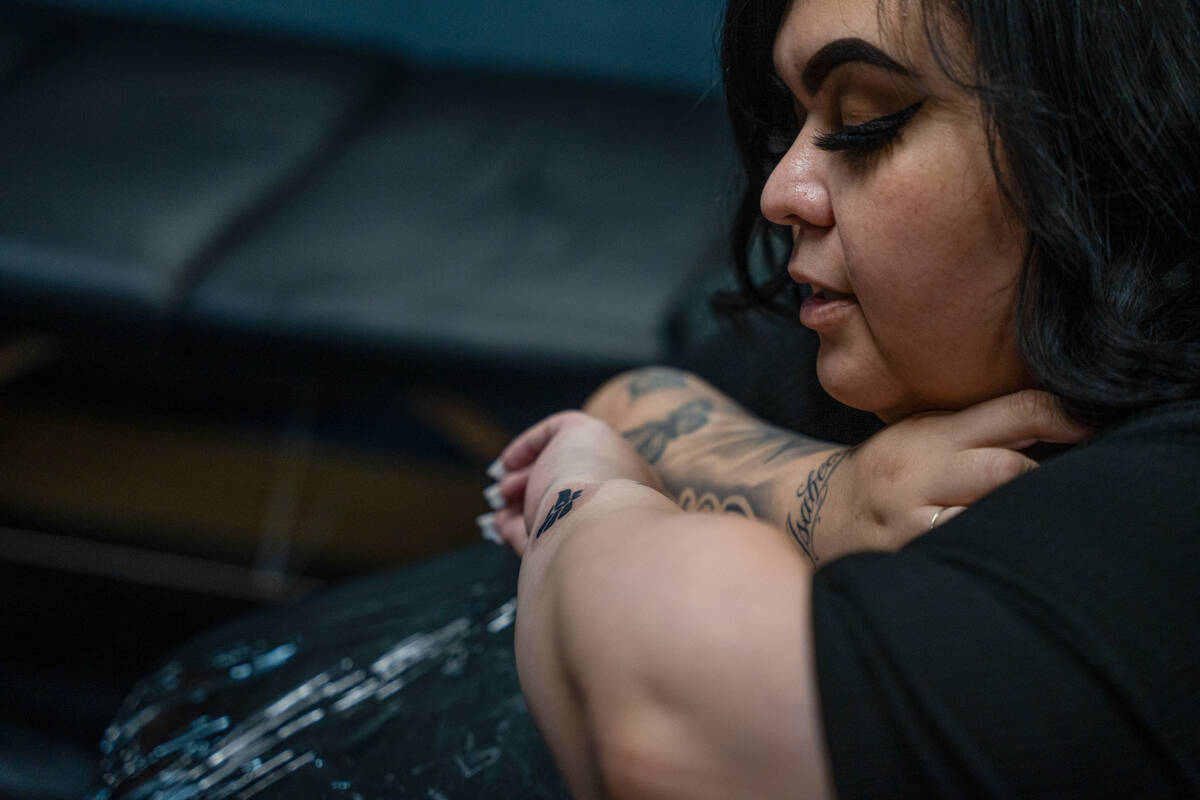 Elizabeth Sanchez checks out her new tattoo after Cindy Angulo finished work during a fundraise ...