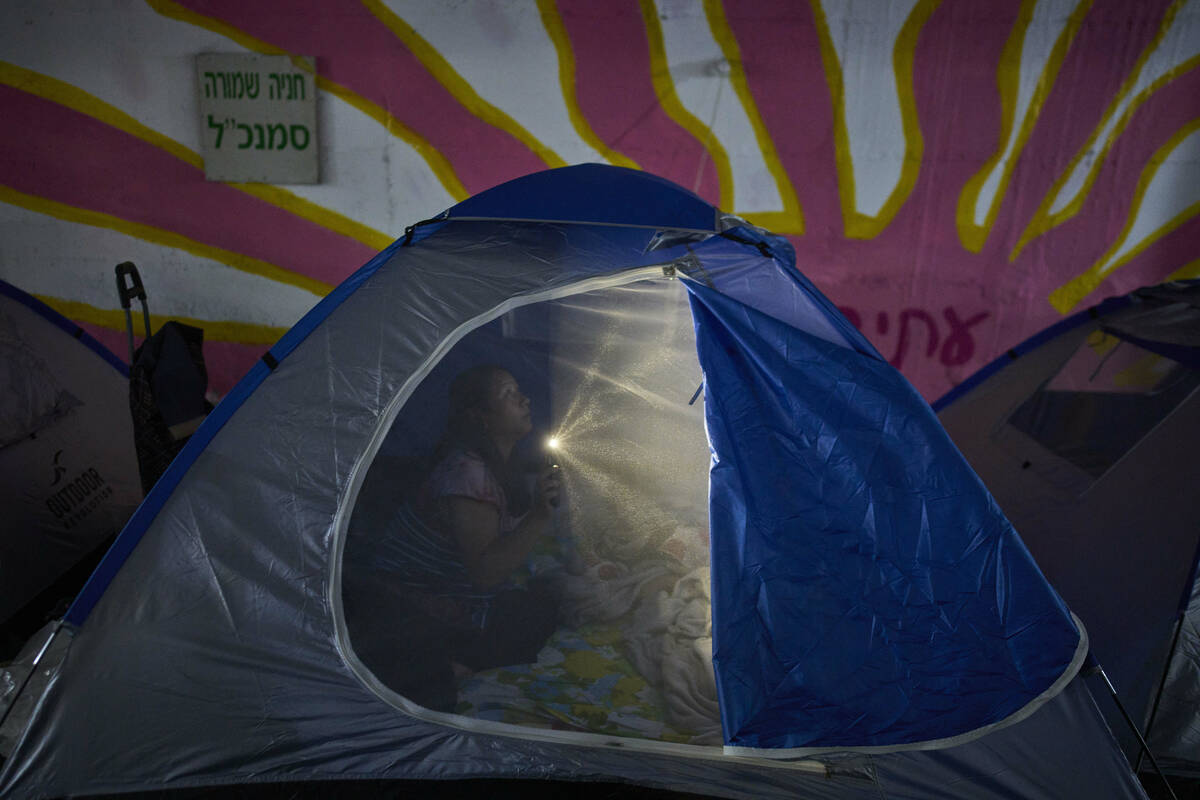A person illuminates a light inside a tent while spending the night in a public shelter as a pr ...