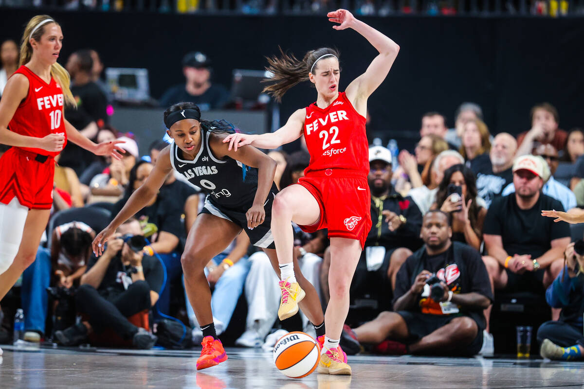Aces guard Jackie Young (0) gets tangled up with Indiana Fever guard Caitlin Clark (22) during ...