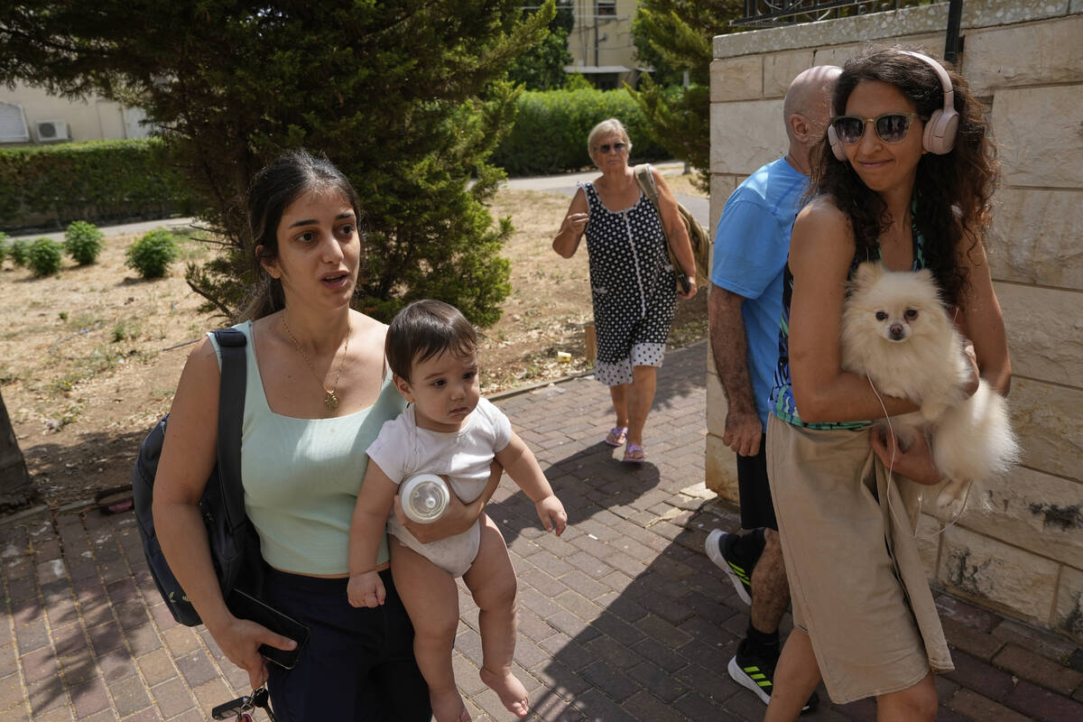 People enter a synagogue's bomb shelter as air raid sirens warn of incoming Iranian strikes in ...