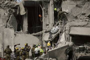 Israeli soldiers and rescue team work amid the rubble of residential buildings destroyed by an ...