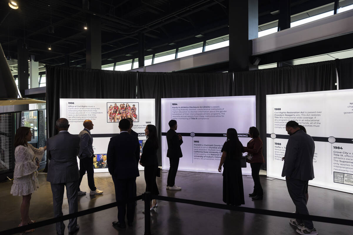 Attendees walk by a timeline of events related to Title IX leading to the red carpet for The IX ...
