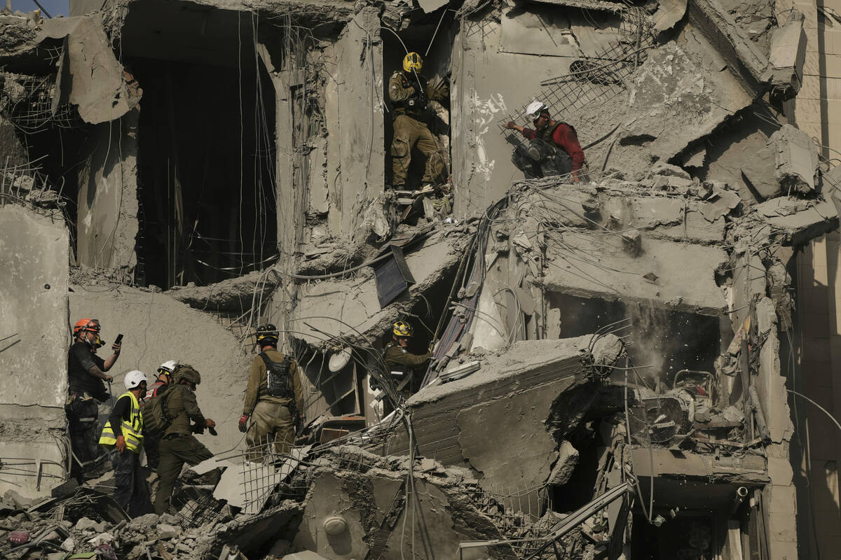 Israeli soldiers and rescue team search for survivors amid the rubble of residential buildings ...