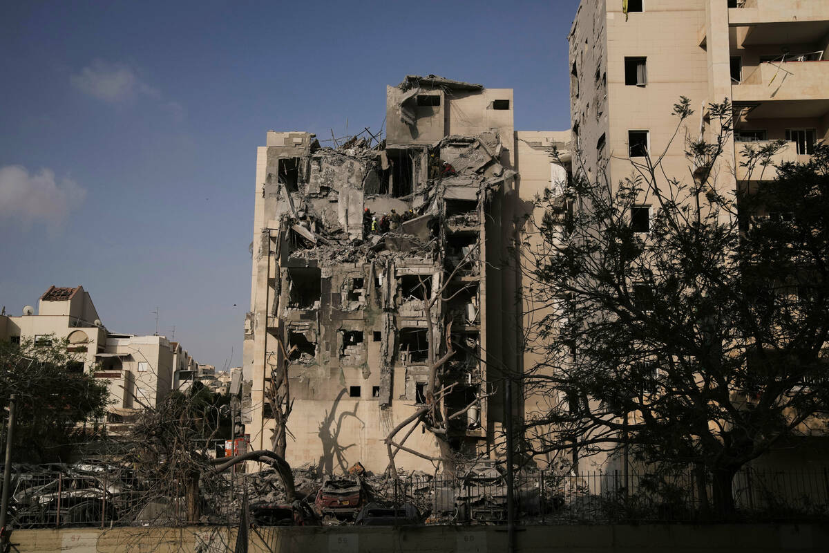 Israeli soldiers and a rescue team search for survivors amid the rubble of residential building ...