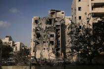 Israeli soldiers and a rescue team search for survivors amid the rubble of residential building ...