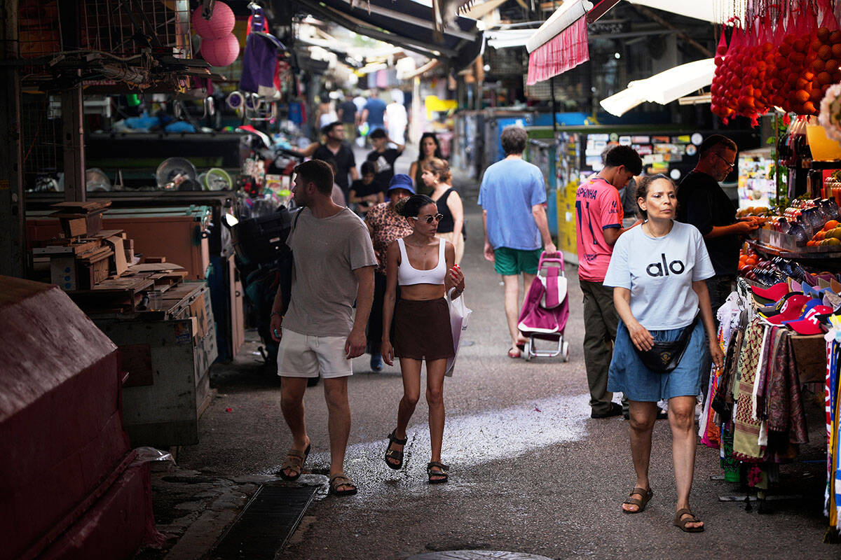 People stroll through an open-air market, hours after U.S. President Donald Trump announced a c ...