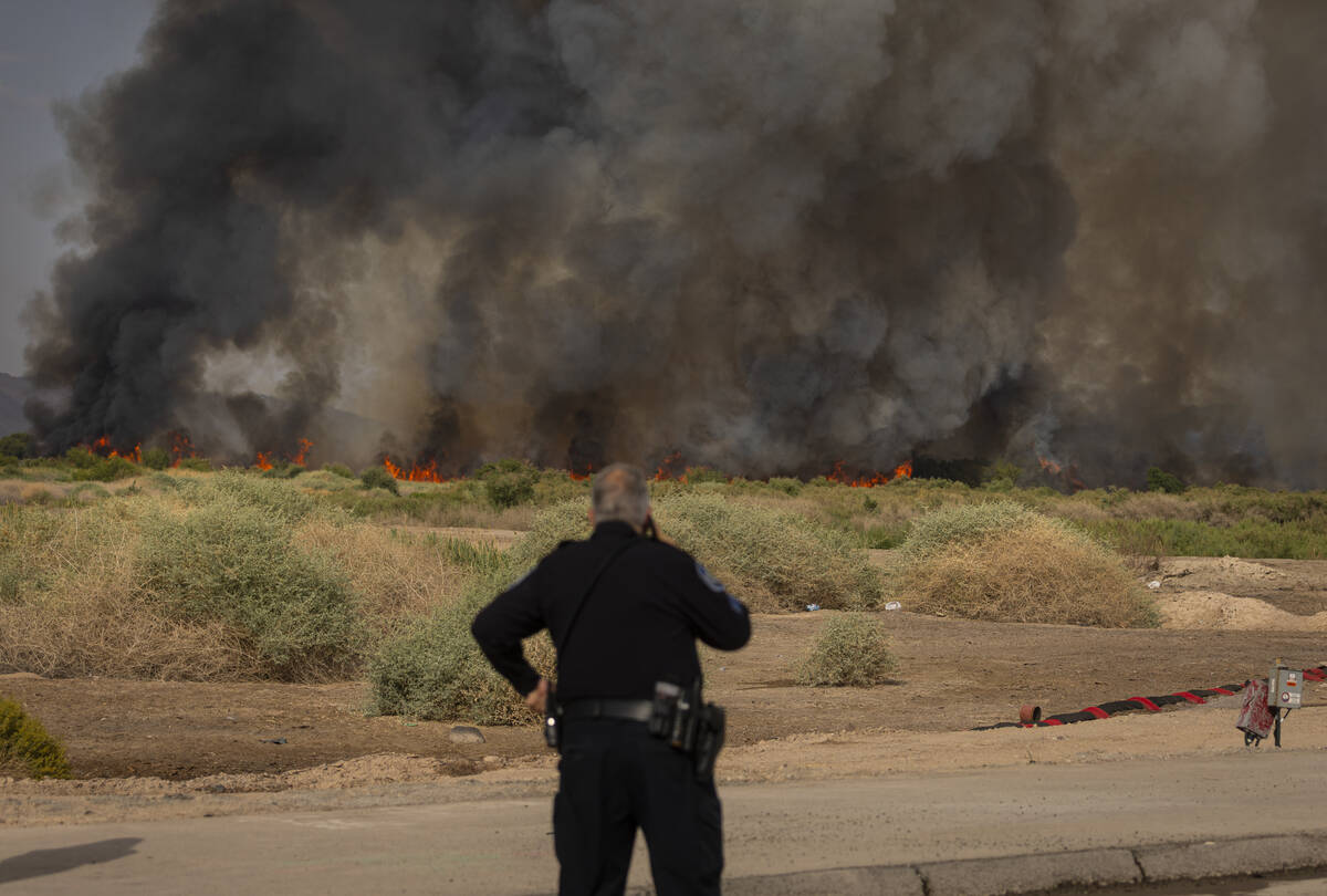 A police officer with the Clark County Office of Public Safety makes a phone call as a fire at ...