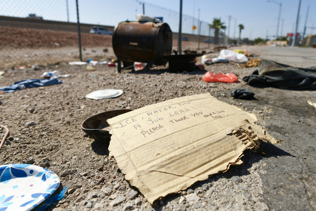 A panhandler’s sign is seen at a vacated homeless encampment along Interstate 11 between the ...