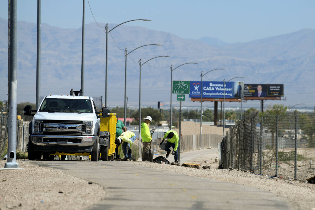 A work crew cleans up detritus from a vacated homeless encampments near Interstate 11 between t ...